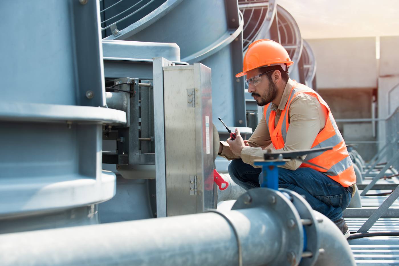 Technician inspecting commercial cooling equipment on a building rooftop